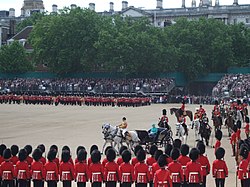 The Queen inspects the foot guards, the Royal Colonels following her. Foreground: backs of No. 6 Guard. Background: garden of 10 Downing Street and massed bands. Trooping the Colour Inspection.JPG