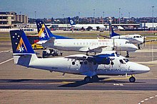 An Aeropelican Twin Otter 300 in front of two Kendell Saab 340s VH-KZN DHC.6 Twin Otter 300 Sero Pelican (op for Ansett) SYD (6814192303).jpg