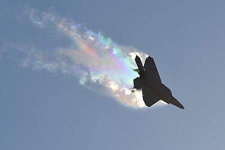 A U.S. Air Force F-22 Raptor banks left causing vapor contrails (32517126414).jpg