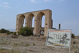 Ruinas del edificio del Teatro Dramático Estatal de Agdam en 2021.  La placa en primer plano muestra el mismo edificio durante la era soviética.