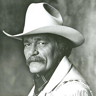 A man with a large mustache wearing a cowboy hat and light-coloured jacket