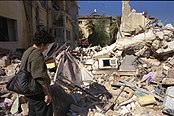 A Siradi woman inspects the ruins of her home after a Mahsadari airstrike, 2000.