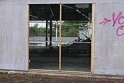 This image depicts a view into what remains of the showroom of the dealership. Already, the wreckers have moved in, but the site's Ford heritage is still very clear through the stickers on the windows.