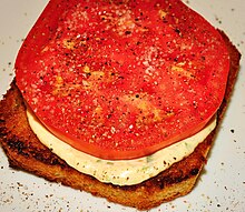 An open-faced tomato sandwich seasoned with salt and pepper atop the tomato Fresh tomato sandwich.jpg