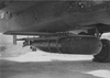 A torpedo, fitted with wings and tail, is mounted under a medium bomber.