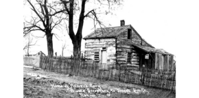 a log cabin on the side of a hill in black-and-white. White writing runs along the bottom.