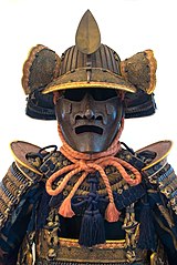 The fukigaeshi can be seen to both sides of the mabizashi (brim), and the shinobi-no-o (cord) secures the mengu (facial armour)