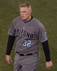 Un hombre con un uniforme de béisbol gris con "Arizona" en el pecho en negro