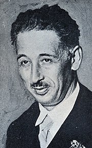 Portrait photo en noir et blanc d'un homme moustachu en costume.