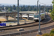 An airport-bound MAX train running above I-205 MAX Around The Curve (6161753154).jpg