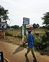 In Ghana, a migrant hawker carries colorful textiles on his head for sale Migrant worker.jpg