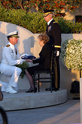 Der Kommandant der USS Ronald Reagan (CVN-76), Capt. James A. Symonds, übergibt Nancy Reagan die Flagge, die den Sarg ihres Mannes umhüllte.