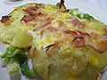 Patata entera cocida al horno, abierta y gratinada con huevos y beicon