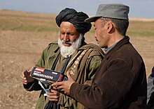 Radio Gureshk -- Afghan Police officer hands out radios keyed to RADIO GURESHK in Mayai Village, Gureshk district, Helmand Province -b.jpg