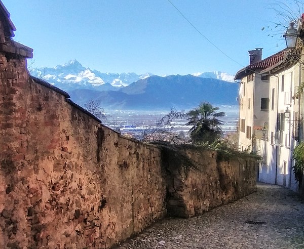 Medieval street with the city wall and Monviso visible in the distance