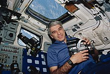 Astronaut Sidney M. Gutierrez, mission commander, pauses on the flight deck during Earth observations on the Space Shuttle Endeavour. Gutierrez, who was joined by five other NASA astronauts for 11-days in Earth orbit, holds a 70mm Hasselblad camera. Sidney Gutierrez (29320041273).jpg