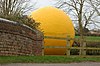 Large yellow sphere part hidden by the brick parapet of a canal bridge