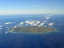 Vue aérienne couleur d'une île, dans une étendue d'eau bleue.