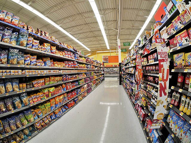 An image displaying a supermarket aisle containing many ultra-processed foods, mainly chips.