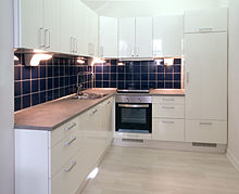 High-gloss finish used for kitchen elements White kitchen with dark blue tiling.jpg