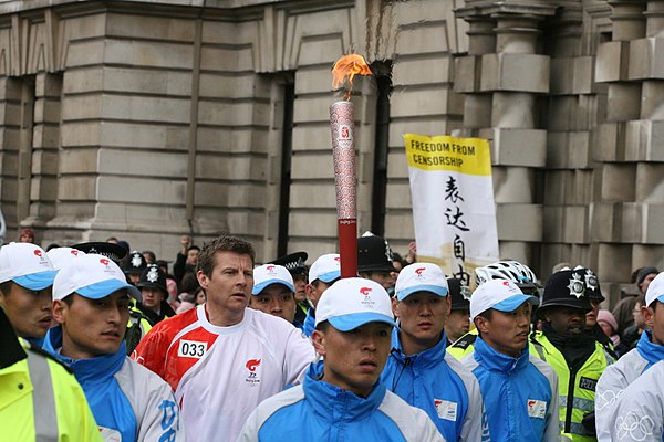 Cram carries the Olympic Torch for the 2008 Summer Olympics down Whitehall in London surrounded by Police and Olympic officials on 6 April 2008