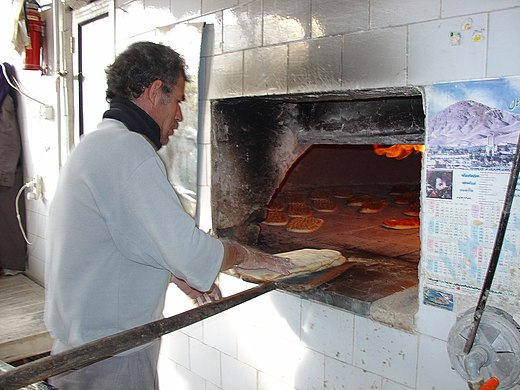 Baker baking Barbari bread in a traditional oven