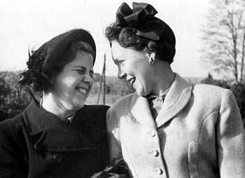 Two Swedish women, circa 1948, in heavy coats. They're looking at each other and sharing a good laugh.