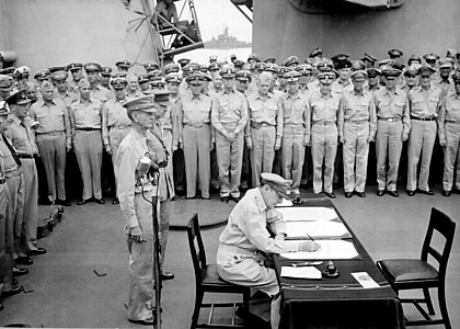 2 Eylül 1945 tarihinde saat 9:08'de Tokyo Körfezi'nin Uraga Kanalı'nda demirleyen USS Missouri (BB-63)'nin güvertesinde Japonya'nın teslimiyet belgesini imzalayan Müttefik Kuvvetler Yüksek Komutanı Douglas MacArthur. Arkasında Filipinler'de teslim olmuş ABD Korgeneral Jonathan Mayhew Wainwright IV ve Singapur'da teslim olmuş İngiliz Korgeneral Arthur Percival görülmektedir. (Üreten: ABD, Library of Congress)