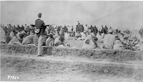 A U.S. soldier stands guard over Navajo people during the Long Walk.