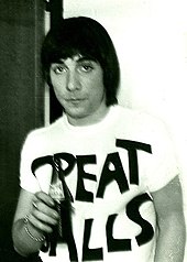 Unsmiling young man in a T-shirt, holding a bottle