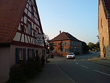 Ortsdurchfahrt Altort in Richtung Norden; links: Wirtshaus, Mitte: historisches Schulhaus, rechts Kirche St. Peter und Paul (2018)