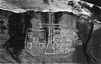 Escudo, com os escudetes em aspa e sem a bordadura de castelos, gravado na Pedra de Ielala pela expedição de Diogo Cão. Cataratas de Ielala no rio Congo, 1485.