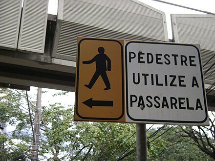 A sign in Belo Horizonte, Brazil, directing pedestrians to an overpass for safe crossing.