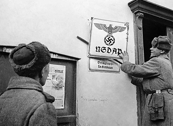 Soviet soldiers taking down a Nazi sign in Austria