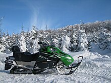 A snowmobile on a snowy mountain.