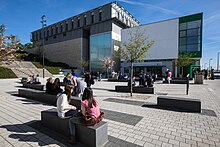 Modern bir binanın önünde öğrenciler