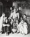 Upasni Maharaj in 1930s seated with his kanyas (nuns), the virgin women who served for many years as his wives. His bamboo cage is visible in the background on the right.