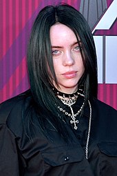 Billie Eilish became the first artist born in the 21st century to have a number-one song on the Hot 100, with "Bad Guy". Billie Eilish 2019 by Glenn Francis (cropped).jpg