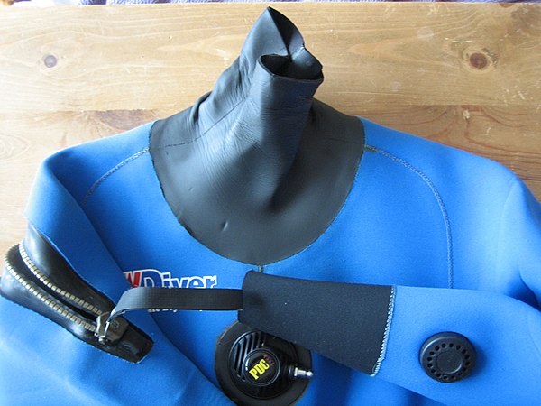 The neck seal, the zip, the inflator, a wrist seal, and the manual cuff vent of a neoprene dry suit