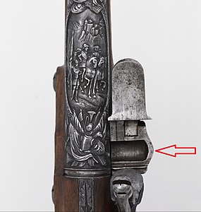 Detalhe de um mecanismo de pederneira onde se pode ver destacado o rebaixo ao lado do cano para colocar a "espoleta" de pólvora.