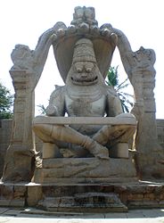 Narasimha, the man-lion incarnation of Vishnu seated on the coils of Shesha, with seven heads of Shesha forming a canopy. Statue at Vijayanagara.