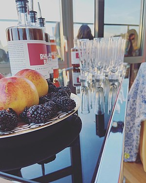 A Pour My Party tasting bar featuring Heimat fresh fruit liqueur alongside a plate of peaches and blackberries