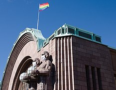 Helsinki Central Station statues with masks and Pride flag.