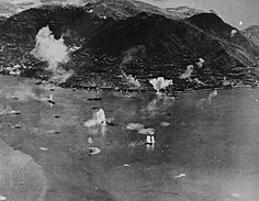 Zdjęcie przedstawia port w Hongkongu w trakcie ataku amerykańskiego lotnictwa 16 stycznia 1945 roku. Na pierwszym planie widać japońskie statki zbombardowane przez Amerykanów.