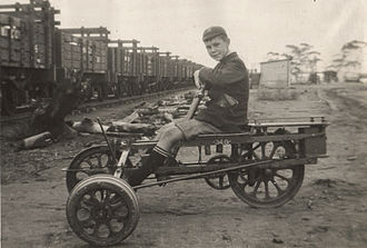 A child on an "Armstrong" distance-measuring trolley on the Kurrawang Wood Line, Western Australia. The caption for this 1928 photo read "These woodlines used to supply timber to the mines and Kalgoorlie Power House. The lines were moved about to follow the salmon gum forests. The rails were leased from the W.A. Govt. Railways by the Timber Co. and once a year this trolley had to be run all over the line and spurs to measure the distance." KurrawangWoodline WEFretwellCollection.jpg