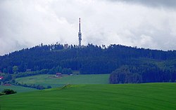 Mezivrata (713 m n. m.) s televizním vysílačem (v popředí vrch Na Kamenech, 568 m n. m.)