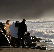 A portable folding reflector positioned to "bounce" sunlight onto a model Photographing a model.jpg