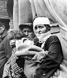 An injured German mother in Heppendorf in need of medical assistance, photographed by a member of the 413th Infantry Regiment (27 February 1945). SC 201463 - A wounded German mother, carrying her baby, awaits medical aid in Heppendorf, Germany, a front-line town captured by infantrymen of the 104th Division, U.S. First Army. (53006004256).jpg