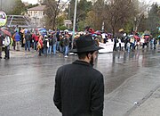 יהודי חרדי בדרכו לקבר שמעון הצדיק חולף על פני הפגנת פעילי שמאל שבועית ביום שישי נגד פינוי המשתכנים