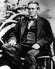 Picture of Abraham Curry seated, a clean-shaven middle-aged man wearing a three-piece suit with a bowtie